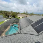 Solar pool heating panels installed on a residential roof overlooking a backyard pool