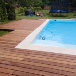 Backyard swimming pool beside a wooden deck