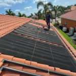 Technician installing solar pool heating panels on a residential roof