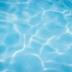 Sunlight reflecting on clear swimming pool water surface