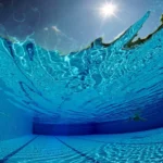 Underwater view of a swimming pool with sunlight shining through the water